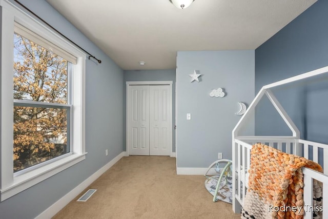 carpeted bedroom featuring baseboards, visible vents, and a closet