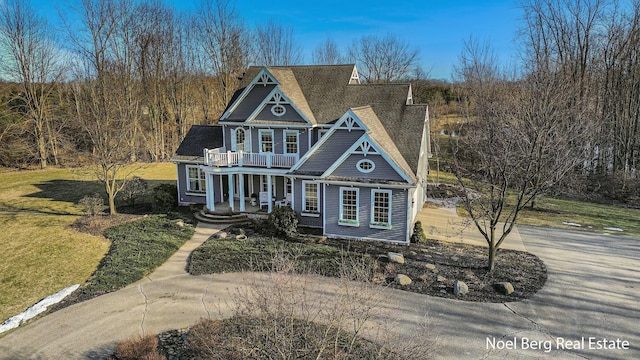 view of front of property featuring a front lawn, a porch, roof with shingles, concrete driveway, and a balcony