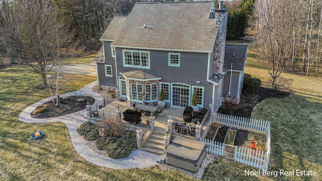 back of property featuring a chimney, roof with shingles, a yard, and fence