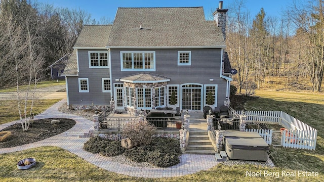 back of property featuring a lawn, fence, a shingled roof, a chimney, and a patio area