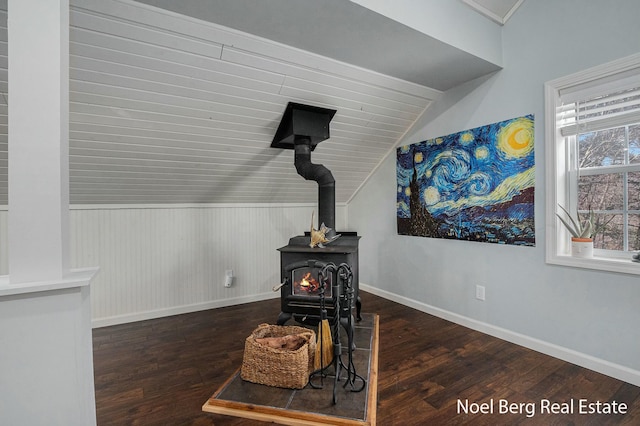 interior details featuring a wood stove, wood finished floors, and baseboards