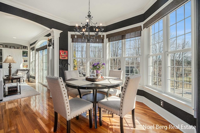 dining area with hardwood / wood-style floors, arched walkways, and ornamental molding