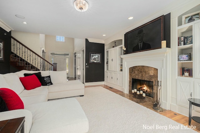 living area featuring built in shelves, wood finished floors, a high end fireplace, recessed lighting, and stairs