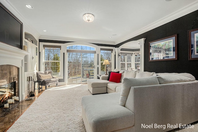 living area with ornamental molding, a tiled fireplace, recessed lighting, dark wood-style flooring, and ornate columns