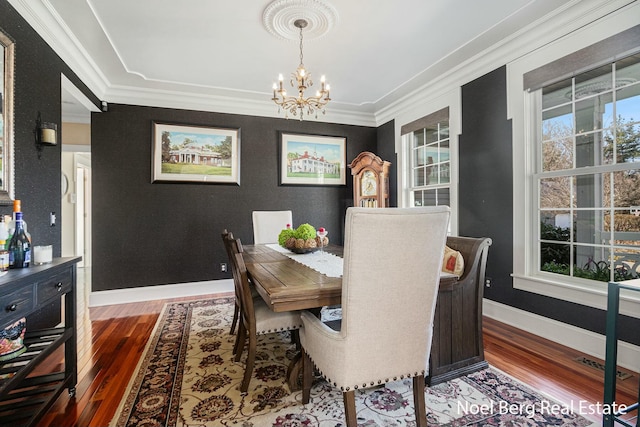 dining room with crown molding, wood finished floors, a wealth of natural light, and a chandelier