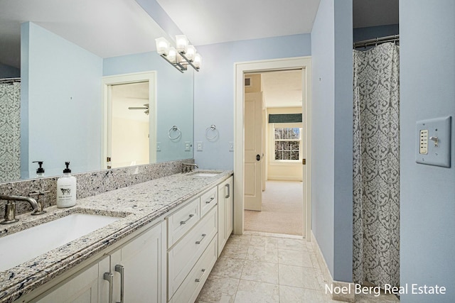 bathroom featuring a sink, baseboards, double vanity, and tile patterned flooring