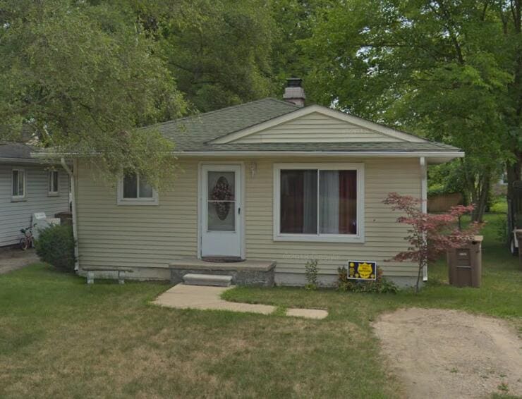 view of front of property featuring a chimney, a front yard, and roof with shingles