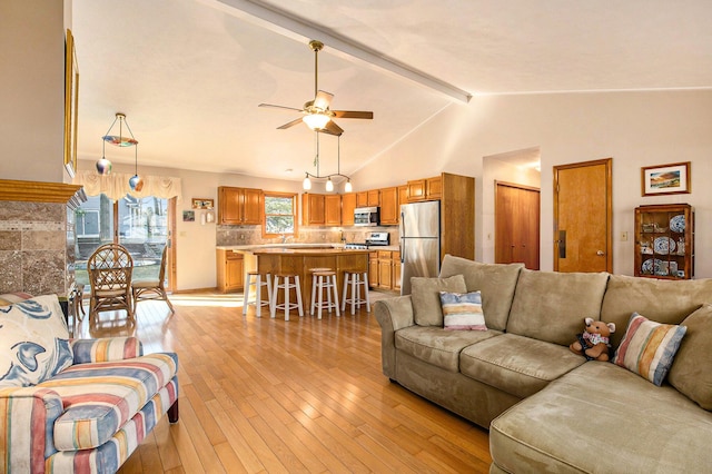 living area with lofted ceiling with beams, a ceiling fan, and light wood finished floors