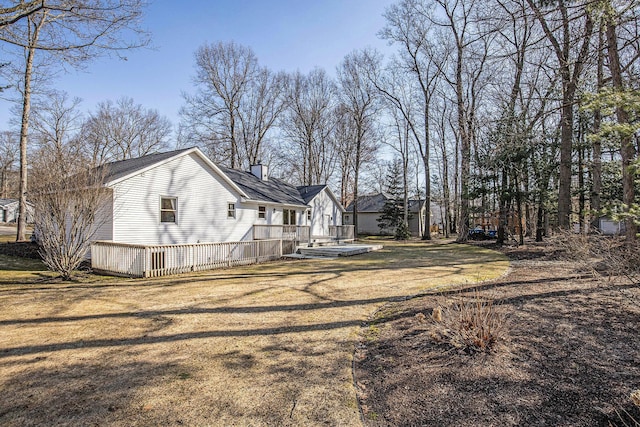 view of property exterior with a chimney, a lawn, and a wooden deck