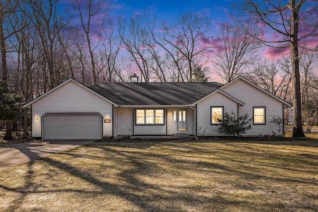 single story home with a chimney, an attached garage, concrete driveway, and a yard