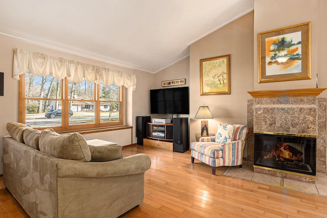 living area featuring lofted ceiling, hardwood / wood-style floors, a fireplace, and crown molding