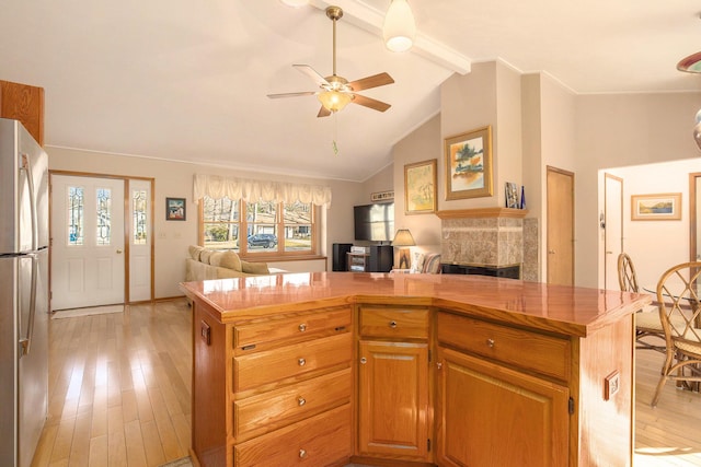 kitchen with light wood finished floors, a kitchen island, vaulted ceiling with beams, open floor plan, and freestanding refrigerator