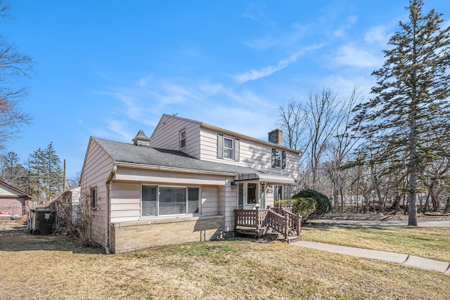 view of front of property featuring brick siding, a chimney, a front yard, and roof with shingles