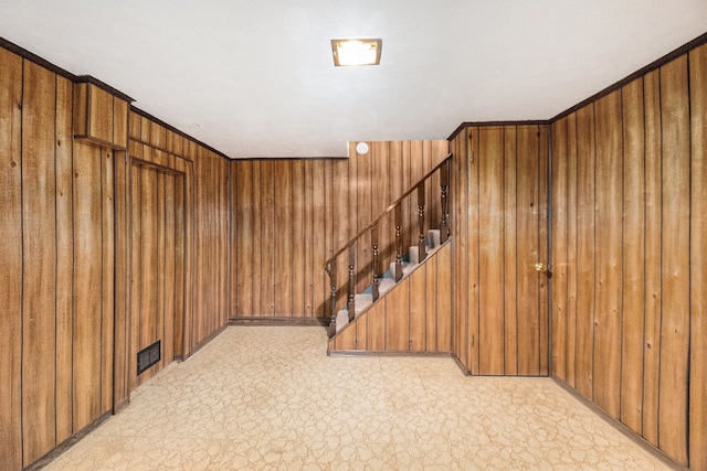 below grade area with wood walls, stairs, and light floors