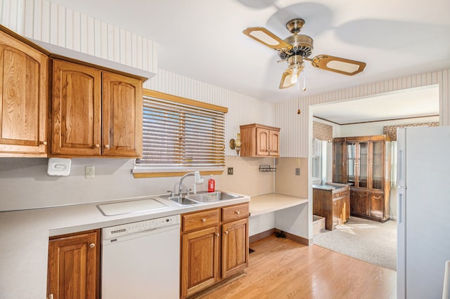 kitchen featuring white appliances, wallpapered walls, a sink, light countertops, and brown cabinets