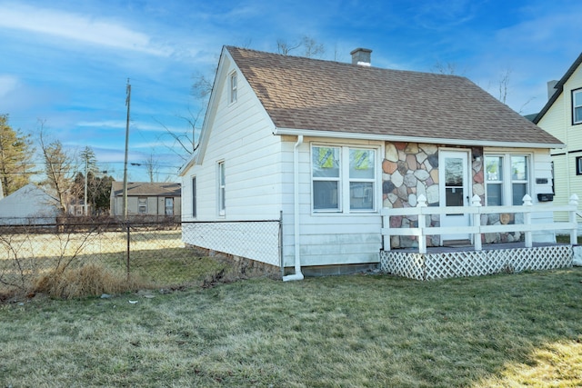 back of property featuring a yard, fence, roof with shingles, and a chimney