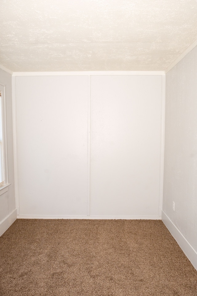 carpeted empty room with a textured ceiling