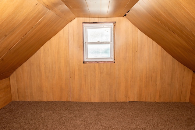 bonus room featuring carpet floors, lofted ceiling, and wood walls