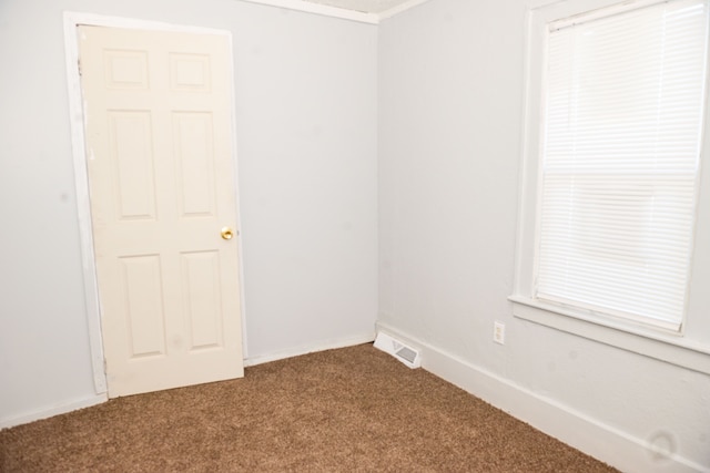 unfurnished room with baseboards, visible vents, and dark carpet