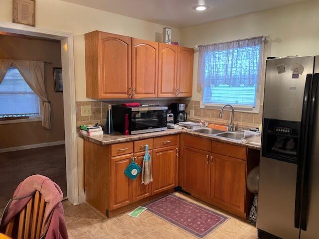 kitchen with brown cabinets, a sink, appliances with stainless steel finishes, decorative backsplash, and baseboards