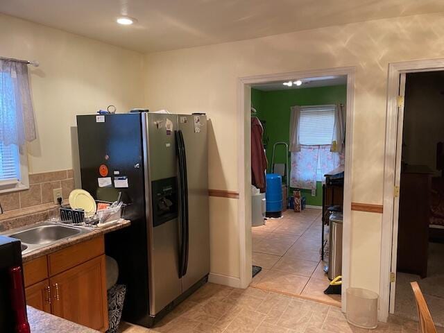 kitchen featuring brown cabinetry, tasteful backsplash, a healthy amount of sunlight, and stainless steel fridge with ice dispenser