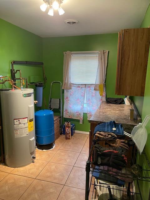 bedroom featuring visible vents, electric water heater, and light tile patterned flooring