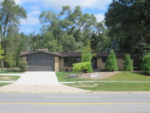 view of front of property with brick siding, a garage, concrete driveway, and a front lawn