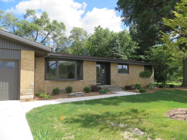 single story home featuring a front yard, an attached garage, and brick siding