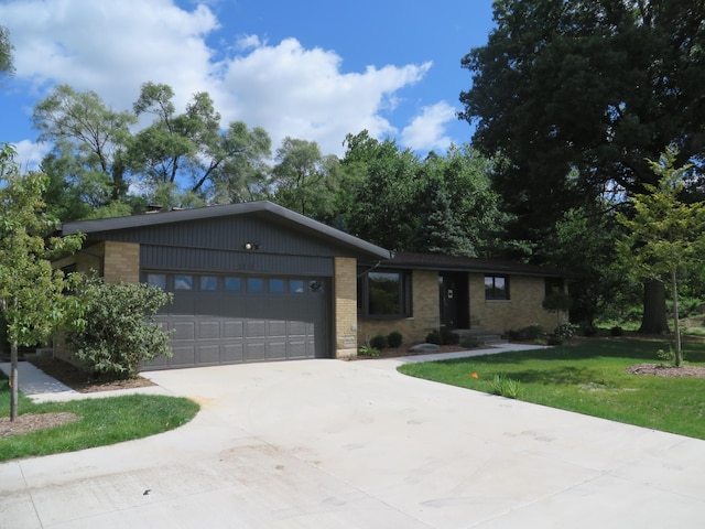 view of front of home featuring concrete driveway, brick siding, a garage, and a front lawn