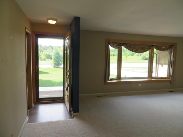 entryway featuring a wealth of natural light, baseboards, light carpet, and visible vents