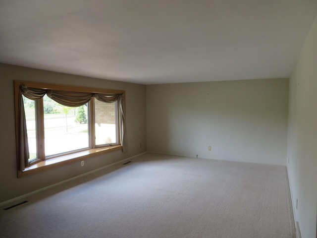 empty room featuring carpet, visible vents, and baseboards