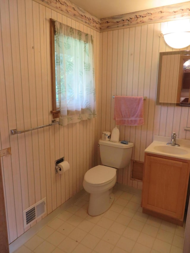 half bathroom featuring visible vents, toilet, wood walls, and vanity