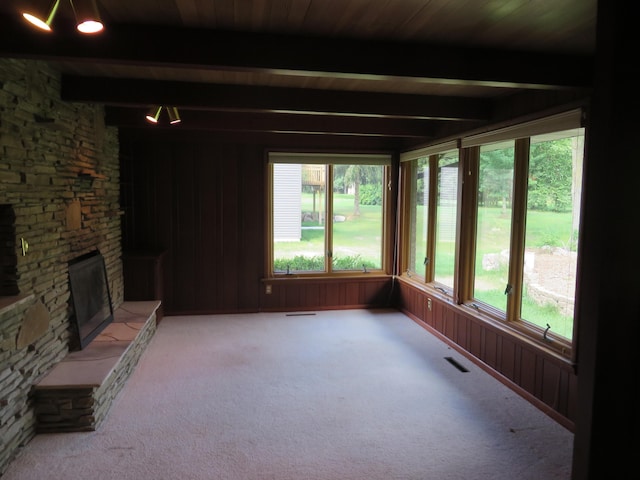 unfurnished sunroom featuring a stone fireplace, beamed ceiling, and visible vents