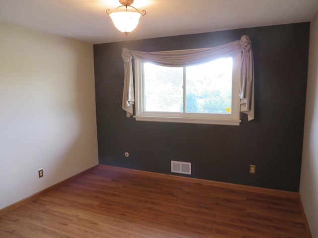 empty room with visible vents, baseboards, and wood finished floors