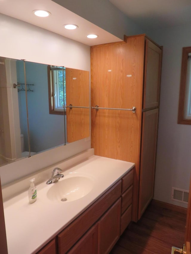 bathroom with visible vents, recessed lighting, vanity, and wood finished floors