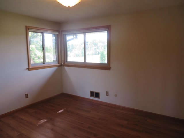 spare room with visible vents, baseboards, and dark wood-type flooring