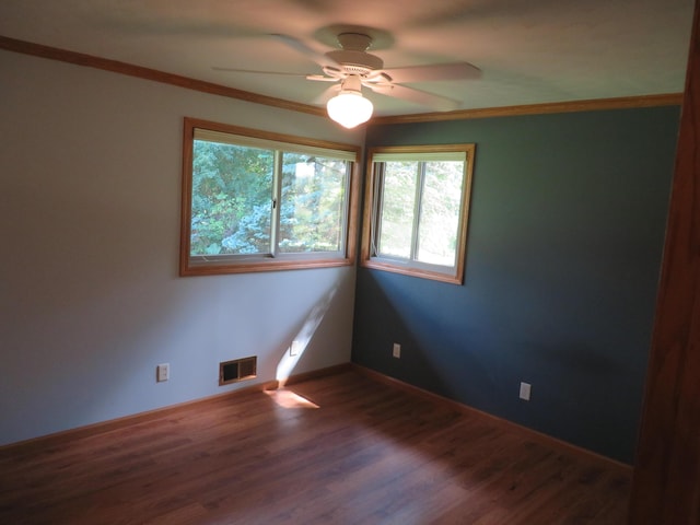 unfurnished room with visible vents, ornamental molding, wood finished floors, baseboards, and ceiling fan