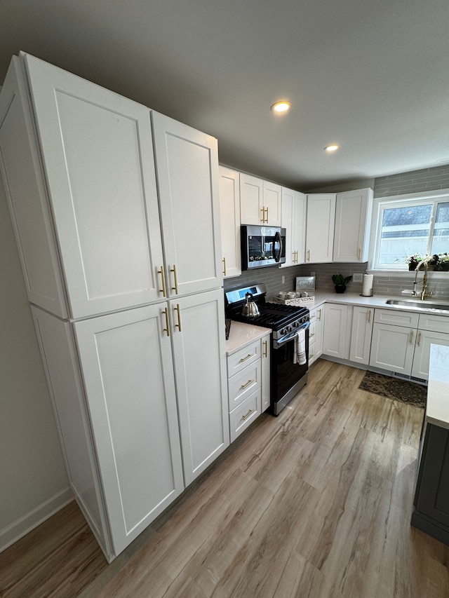 520 E Evelyn Ave, Hazel Park, MI 48030 - kitchen featuring light countertops, appliances with stainless steel finishes, light wood-style floors, white cabinets, and a sink