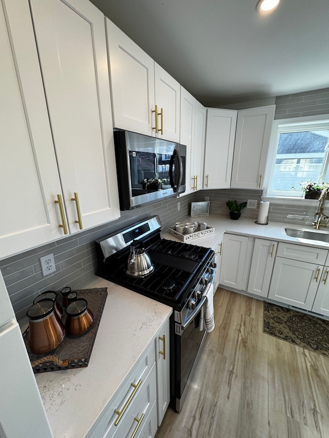 kitchen with backsplash, appliances with stainless steel finishes, and a sink