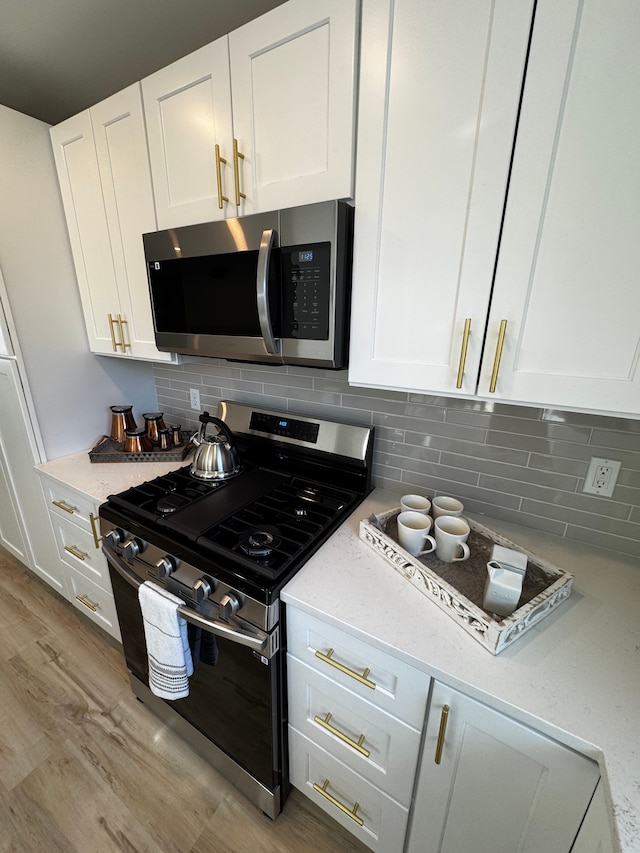 kitchen featuring backsplash, light wood-type flooring, light stone counters, appliances with stainless steel finishes, and white cabinets