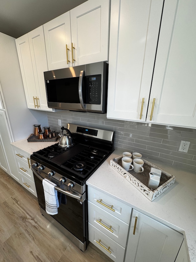520 E Evelyn Ave, Hazel Park, MI 48030 - kitchen featuring light stone countertops, stainless steel appliances, white cabinets, light wood-type flooring, and backsplash