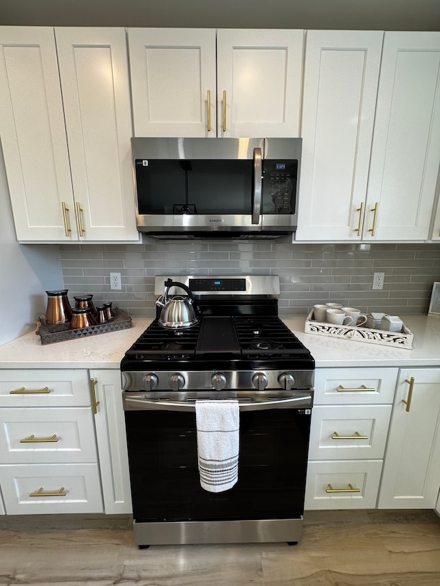 kitchen featuring backsplash, white cabinetry, stainless steel appliances, and light countertops