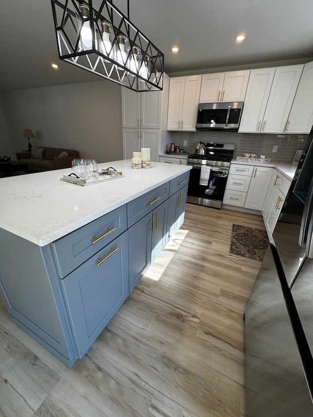 kitchen featuring light wood finished floors, decorative backsplash, appliances with stainless steel finishes, and white cabinetry