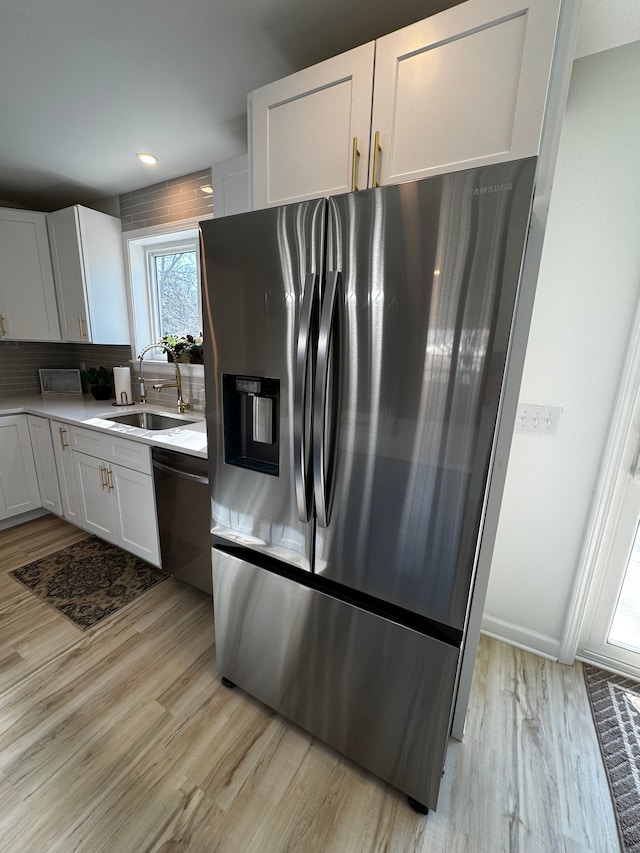 kitchen with a sink, dishwashing machine, light wood-style flooring, and stainless steel refrigerator with ice dispenser