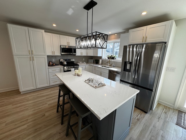 kitchen featuring decorative backsplash, a kitchen breakfast bar, light wood-style floors, and appliances with stainless steel finishes