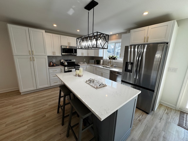 520 E Evelyn Ave, Hazel Park, MI 48030 - kitchen with light wood-type flooring, stainless steel appliances, a kitchen breakfast bar, and decorative backsplash