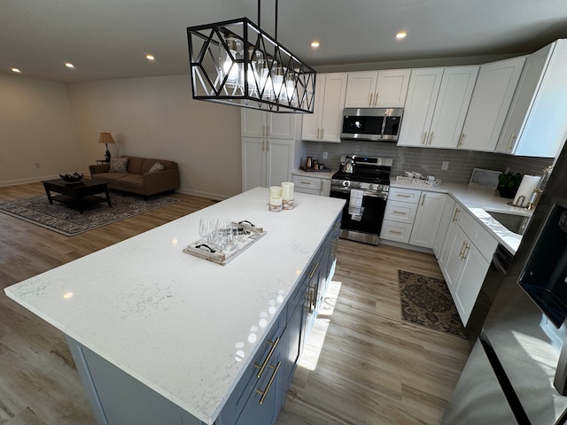 kitchen featuring white cabinets, a center island, open floor plan, and stainless steel appliances