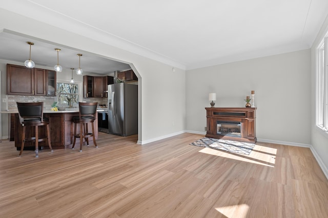 living room with a glass covered fireplace, arched walkways, a wealth of natural light, and light wood-type flooring