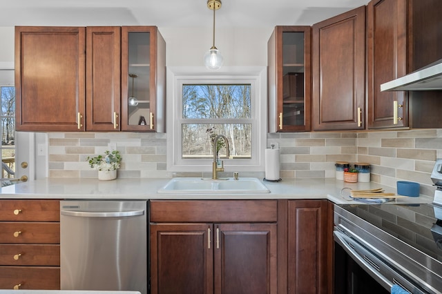 kitchen featuring wall chimney exhaust hood, stainless steel appliances, light countertops, and a sink