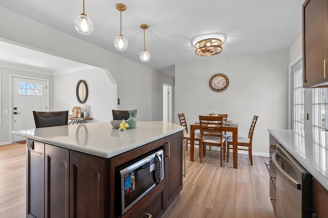 kitchen featuring built in microwave, dark brown cabinetry, light countertops, light wood-type flooring, and stainless steel dishwasher